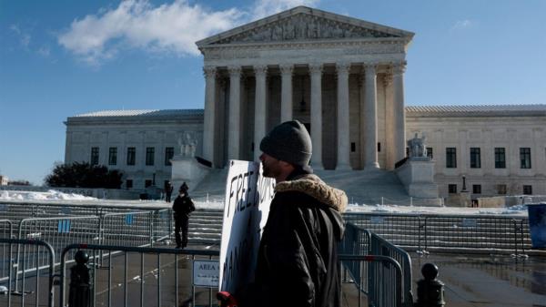 A protestor with a sign stands outside the U.S. Supreme Court. 