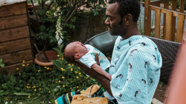 man holding newborn baby outdoors