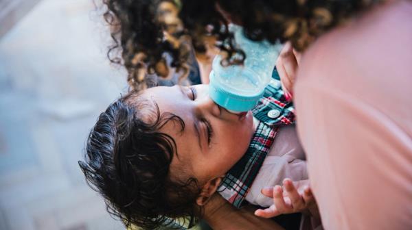 parent feeding baby a bottle