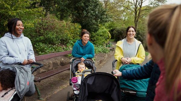 mom friends pushing strollers gather to talk