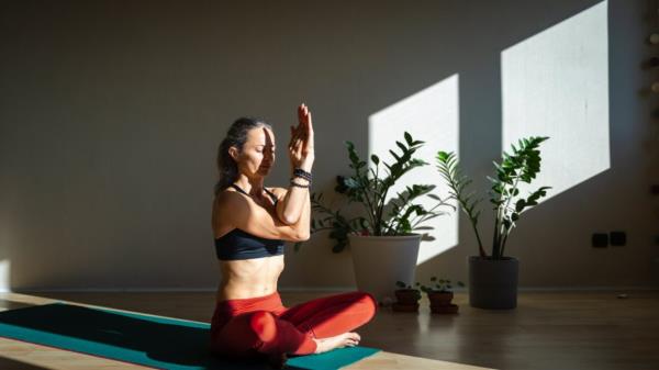 woman sitting crosslegged on floor holding yoga pose 3