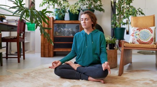 woman sitting on floor meditating in front of plants