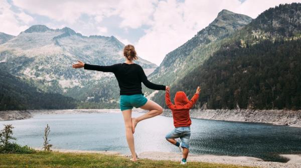 woman and child do yoga by a lake