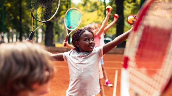 closeup of little girl in group of kids playing tennis