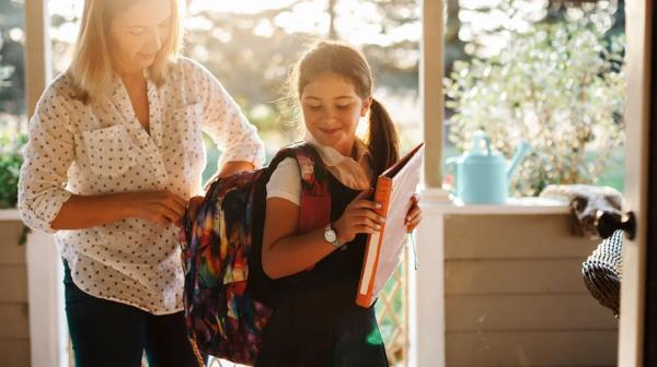 parent helps child prepare school backpack