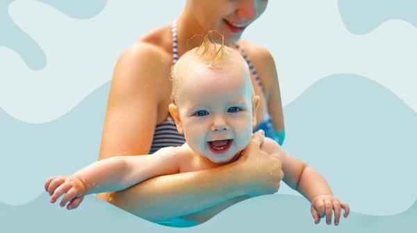 A baby in a parents' arms covered in water from splashes at a swimming pool. 