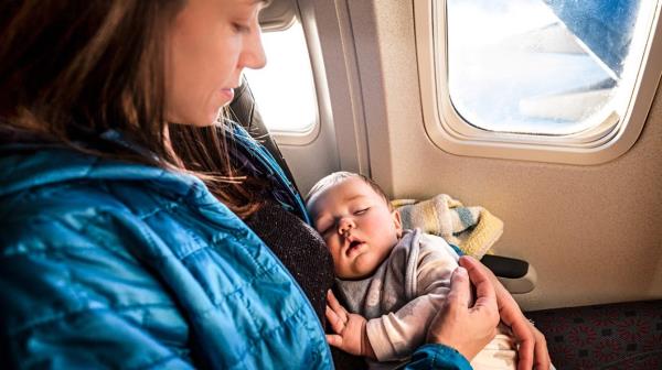 Woman seated on airplane with baby in her lap