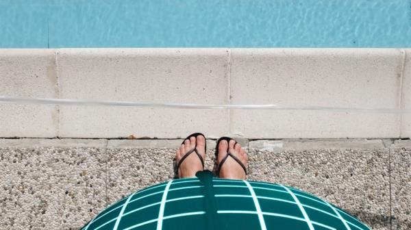 pregnant person stands next to swimming pool
