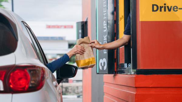 A person picks up fast food at a drive thru window.
