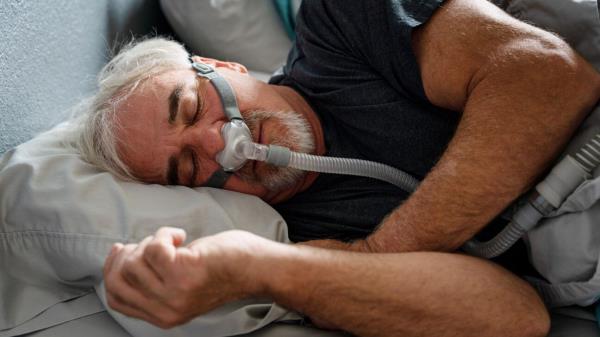 Man wears a CPAP machine while sleeping.